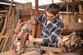 Young Caucasian carpenter man is fixking the sawing machine in his own garage style workshop for hobby Royalty Free Stock Photo