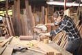 Young Caucasian carpenter man is sawing plank of wood in his own garage style workshop for hobby Royalty Free Stock Photo