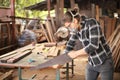 Young Caucasian carpenter man is sawing plank of wood in his own garage style workshop for hobby Royalty Free Stock Photo