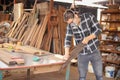 Young Caucasian carpenter man is sawing plank of wood in his own garage style workshop for hobby Royalty Free Stock Photo