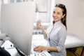 Young Caucasian cheerful female doctor with ultrasound sensor, using modern ultrasound machine, smiling and looking at Royalty Free Stock Photo