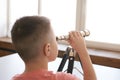 Young caucasian child looking through telescope indoors by window Royalty Free Stock Photo
