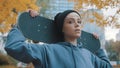 Young caucasian confident woman skater holding skateboard behind her head in the park in autumn Royalty Free Stock Photo