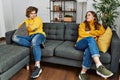 Young caucasian couple angry sitting on sofa at home