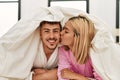 Young caucasian couple covering with bedsheet and smiling happy lying on the bed at home Royalty Free Stock Photo