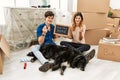 Young caucasian couple with dog holding our first home blackboard at new house doing money gesture with hands, asking for salary Royalty Free Stock Photo