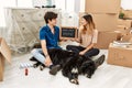 Young caucasian couple with dog holding our first home blackboard at new house looking to side, relax profile pose with natural Royalty Free Stock Photo