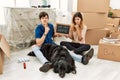 Young caucasian couple with dog holding our first home blackboard at new house thinking concentrated about doubt with finger on Royalty Free Stock Photo