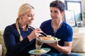 Young Caucasian couple eating Asian traditional food at home