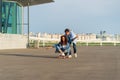 Young couple enjoy skateboarding together on street. Hipster man push back of woman sit on longboard Royalty Free Stock Photo