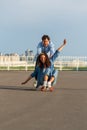 Young couple enjoy skateboarding together on street. Hipster man push back of woman sit on longboard Royalty Free Stock Photo