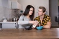 young Caucasian couple having breakfast at home. A woman pours milk for her husband into a bowl of cereal. Royalty Free Stock Photo