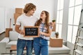 Young caucasian couple holding our new home blackboard hugging each other at new home Royalty Free Stock Photo