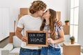 Young caucasian couple holding our new home blackboard kissing and hugging each other at new home Royalty Free Stock Photo