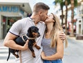 Young caucasian couple hugging and kissing standing with dog at the city Royalty Free Stock Photo