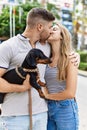 Young caucasian couple hugging and kissing standing with dog at the city Royalty Free Stock Photo