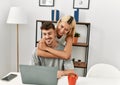 Young caucasian couple hugging and using laptop sitting on the desk at home Royalty Free Stock Photo