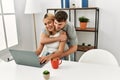 Young caucasian couple hugging and using laptop sitting on the desk at home Royalty Free Stock Photo