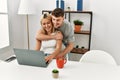 Young caucasian couple hugging and using laptop sitting on the desk at home Royalty Free Stock Photo