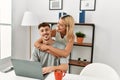 Young caucasian couple hugging and using laptop sitting on the desk at home Royalty Free Stock Photo