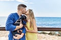 Young caucasian couple kissing and hugging with dog at the beach