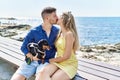 Young caucasian couple kissing and sitting on the bench with dog at the beach Royalty Free Stock Photo