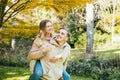 Young caucasian couple in love having fun during a walk in nature. Happy woman enjoying a piggyback ride on boyfriends Royalty Free Stock Photo