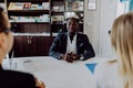 Young caucasian couple at meeting with african american man in formal wear talking at table in modern office Royalty Free Stock Photo