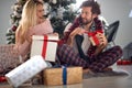 Young couple opening Christmas presents, smiling, looking each other, sitting on the floor in pajamas Royalty Free Stock Photo