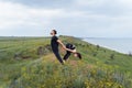 Young caucasian couple practicing acro yoga together on the hill near the sea. Couple, partner yoga. Athlete flexing beautifully