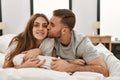 Young caucasian couple smiling happy and kissing on the bed at home Royalty Free Stock Photo