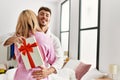 Young caucasian couple smiling happy surprising with anniversary gift bedroom