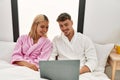 Young caucasian couple smiling happy using laptop sitting on the bed at home Royalty Free Stock Photo