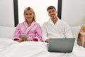 Young caucasian couple smiling happy using laptop and smartphone sitting on the bed at home Royalty Free Stock Photo