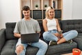 Young caucasian couple smiling happy using laptop and smartphone sitting on the sofa at home Royalty Free Stock Photo