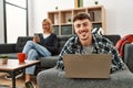 Young caucasian couple smiling happy using laptop and smartphone sitting on the sofa at home Royalty Free Stock Photo