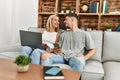 Young caucasian couple smiling happy using laptop and smartphone sitting on the sofa at home Royalty Free Stock Photo