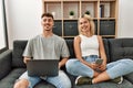 Young caucasian couple smiling happy using laptop and smartphone sitting on the sofa at home Royalty Free Stock Photo