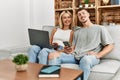 Young caucasian couple smiling happy using laptop and smartphone sitting on the sofa at home Royalty Free Stock Photo