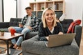 Young caucasian couple smiling happy using laptop and smartphone sitting on the sofa at home Royalty Free Stock Photo