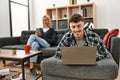 Young caucasian couple smiling happy using laptop and smartphone sitting on the sofa at home Royalty Free Stock Photo