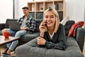 Young caucasian couple smiling happy using laptop and talking on the smartphone at home Royalty Free Stock Photo