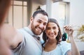 Young caucasian couple taking a selfie holding house keys. Happy couple moving into their house. Smiling couple taking a Royalty Free Stock Photo