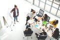 Young caucasian creative man standing and making presentation at modern office happy talking and brainstorming with team. Royalty Free Stock Photo