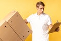 Young caucasian delivery man holding and carrying cardbox isolated on yellow background Royalty Free Stock Photo