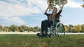 Young caucasian disabled woman listening music and hand dancing under the tree. wide angle