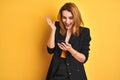 Young caucasian elegant business woman using smartphone over isolated yellow background very happy and excited, winner expression Royalty Free Stock Photo