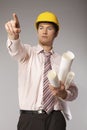 Young caucasian engineer with plans pointing finger away Royalty Free Stock Photo