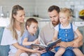 Young caucasian family reading a book together on the couch at home. Mother and father teaching their little son and Royalty Free Stock Photo