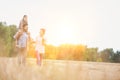 Young Caucasian family walking across field with young child on her fathers shoulders with the wife holding a bouquet of flowers